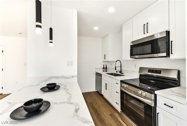 kitchen featuring stainless steel appliances, a sink, dark wood-style flooring, light stone countertops, and white cabinetry