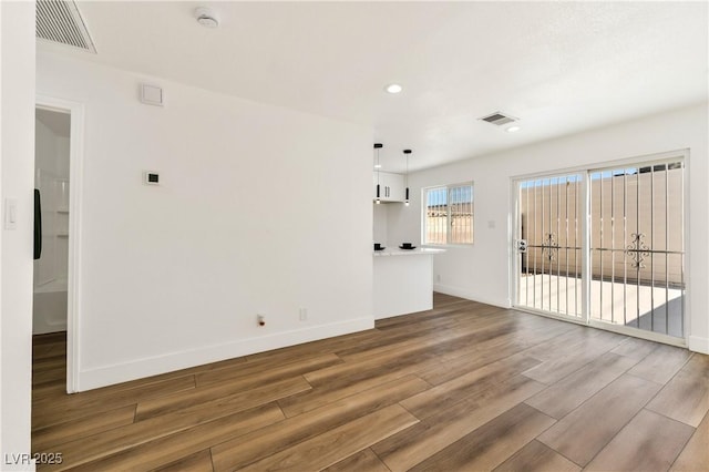 unfurnished living room with wood finished floors, baseboards, and recessed lighting