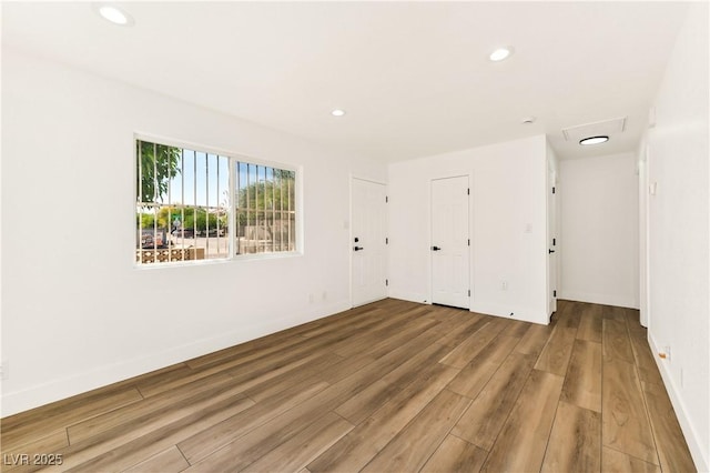 empty room with wood finished floors, recessed lighting, and baseboards