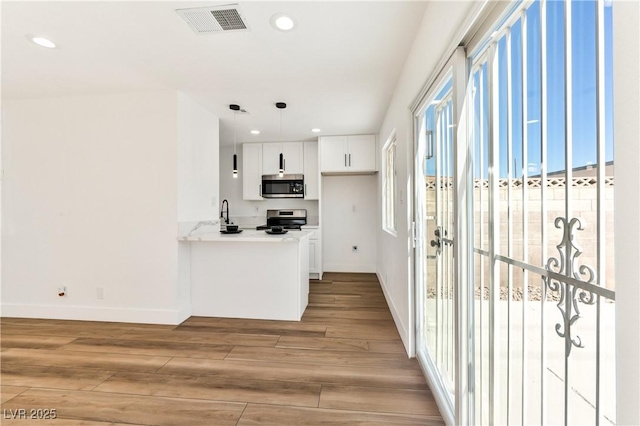 kitchen with appliances with stainless steel finishes, light wood-style floors, baseboards, recessed lighting, and pendant lighting