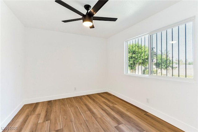 spare room featuring baseboards, wood finished floors, and a ceiling fan