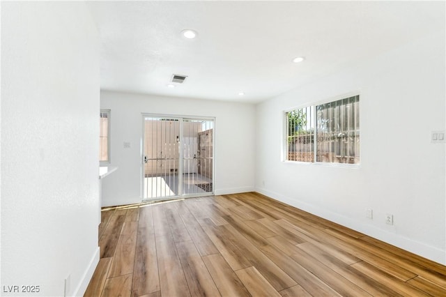 spare room with plenty of natural light, wood finished floors, baseboards, and recessed lighting