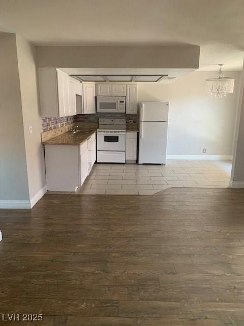 kitchen featuring white appliances, baseboards, dark countertops, a chandelier, and wood finished floors