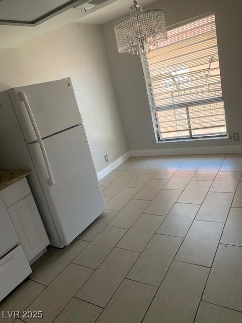 unfurnished dining area featuring baseboards and a chandelier