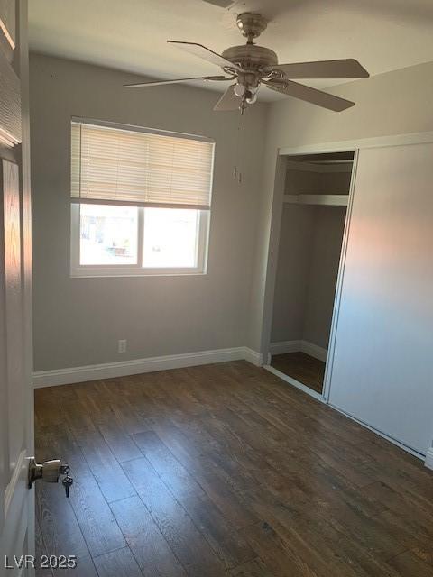 unfurnished bedroom featuring wood finished floors, a ceiling fan, a closet, and baseboards