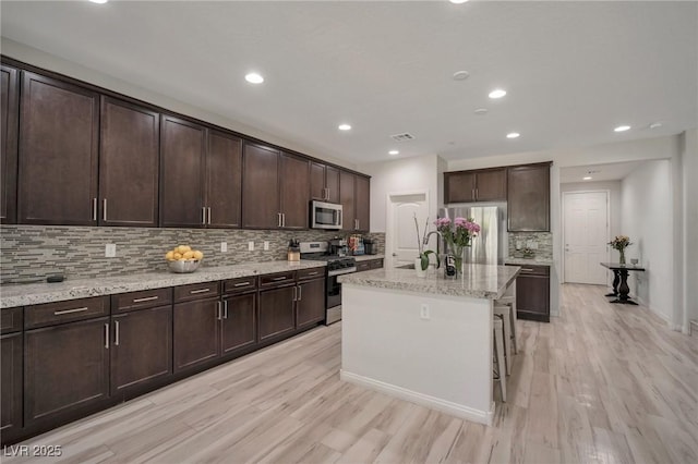 205 Piedmont Alps St, Henderson, NV 89012 - kitchen with appliances with stainless steel finishes, backsplash, light wood-style floors, dark brown cabinets, and a sink