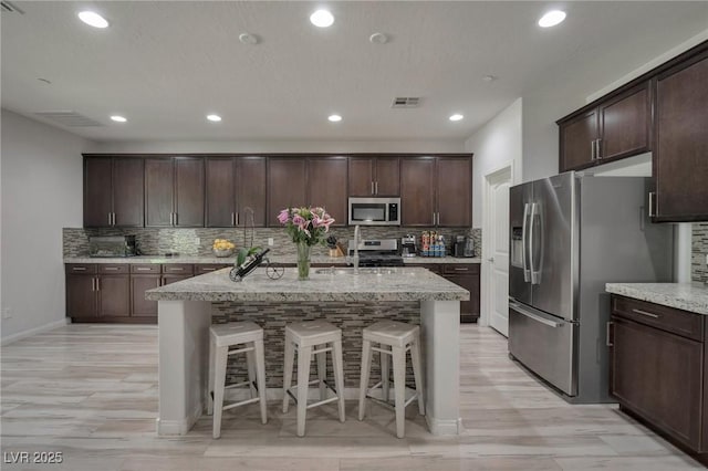 205 Piedmont Alps St, Henderson, NV 89012 - kitchen with appliances with stainless steel finishes, backsplash, a center island with sink, dark brown cabinets, and recessed lighting