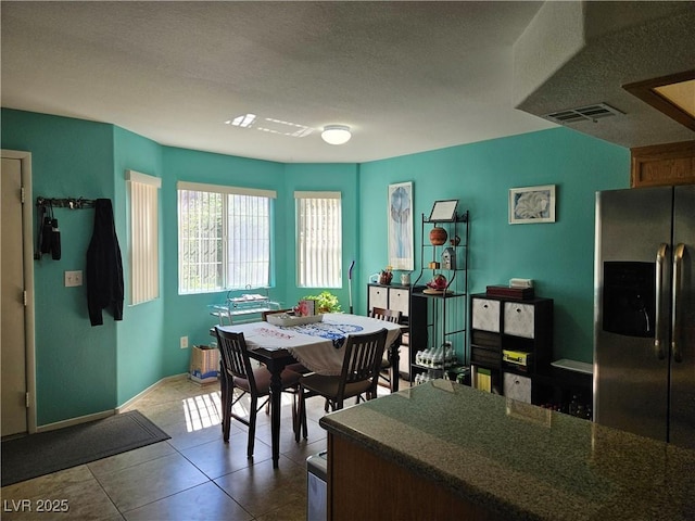 dining area with a textured ceiling, dark tile patterned flooring, and baseboards