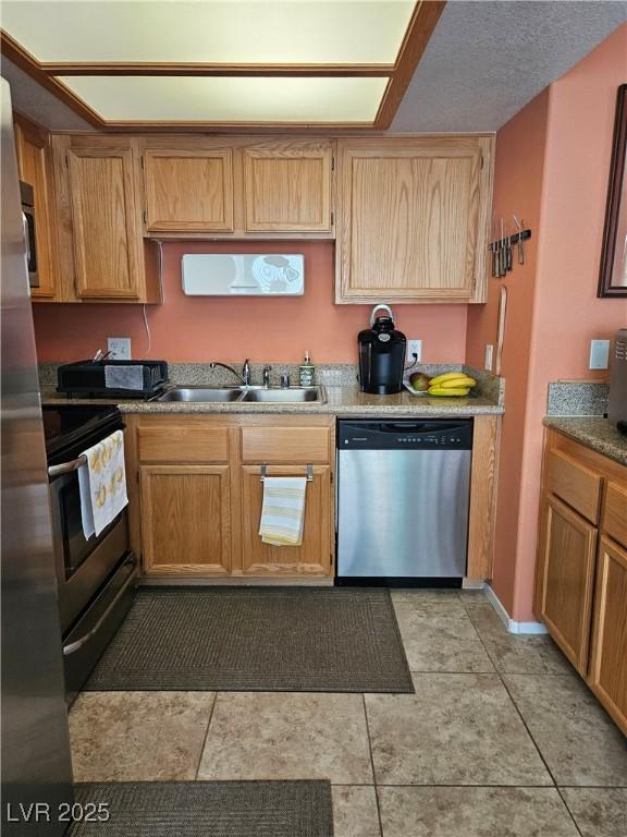 kitchen with appliances with stainless steel finishes, a sink, and light tile patterned floors