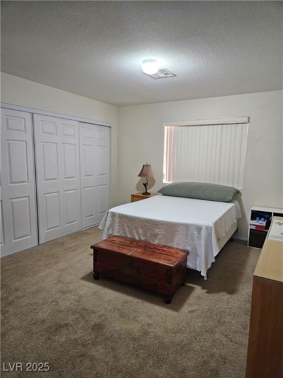 bedroom with carpet floors, a textured ceiling, and a closet