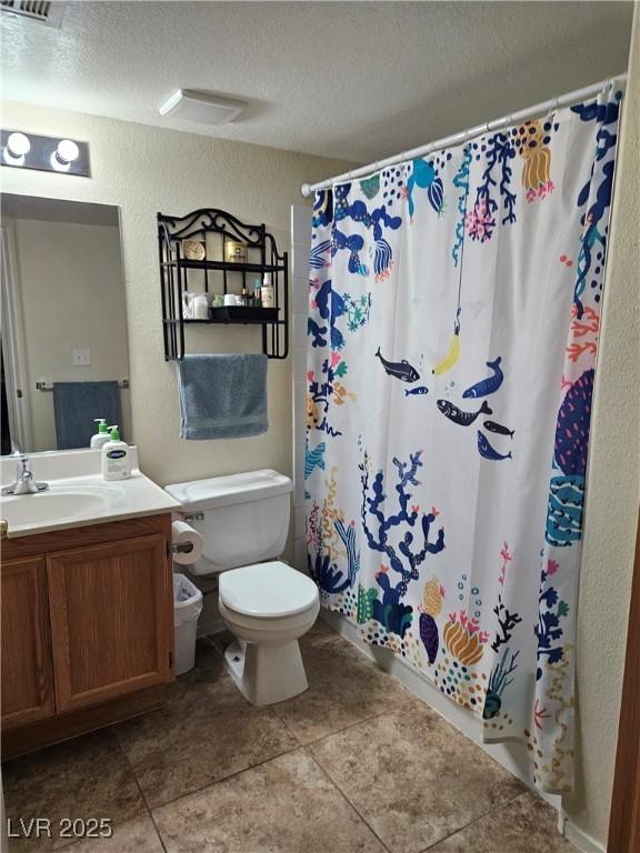 bathroom featuring a textured wall, toilet, tile patterned floors, vanity, and curtained shower