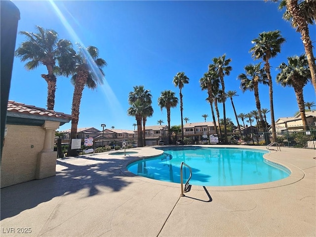 community pool featuring fence, a patio, and a residential view