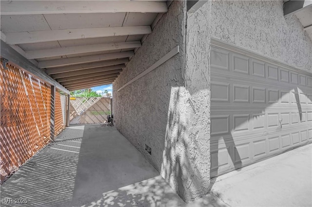 view of property exterior with stucco siding, fence, and a garage