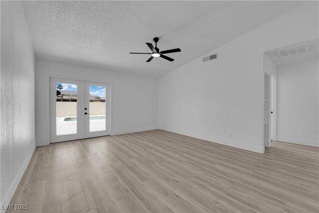 empty room featuring french doors, light wood finished floors, a textured ceiling, a ceiling fan, and baseboards