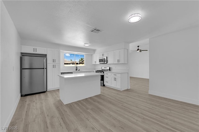 kitchen with stainless steel appliances, white cabinetry, baseboards, and light countertops