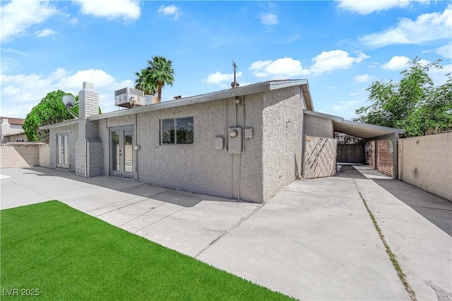 back of property with fence, french doors, a chimney, and stucco siding