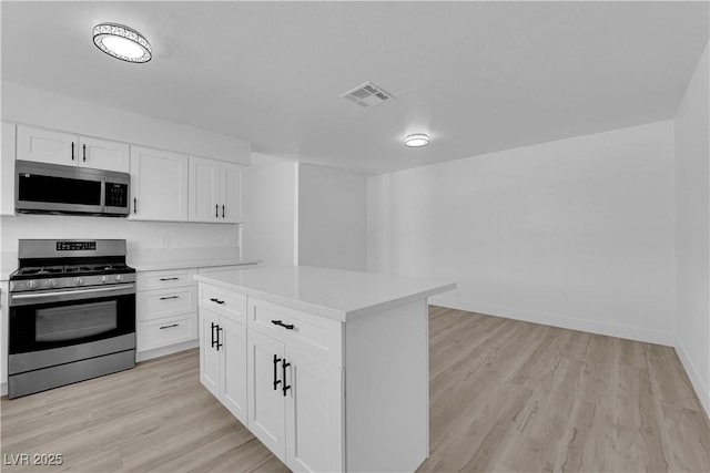 kitchen with appliances with stainless steel finishes, light countertops, light wood-style flooring, and white cabinetry
