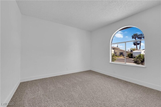 empty room featuring carpet flooring, a textured ceiling, and baseboards