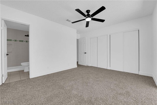 unfurnished bedroom with multiple closets, carpet, connected bathroom, a textured ceiling, and baseboards
