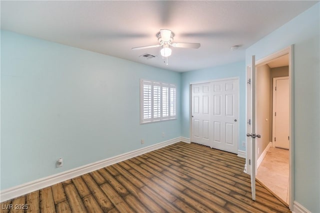 unfurnished bedroom featuring baseboards, wood finished floors, a closet, and a ceiling fan