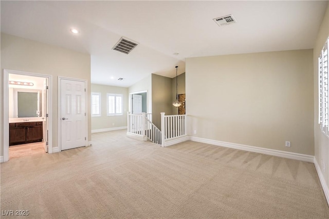 empty room featuring baseboards, vaulted ceiling, and light colored carpet