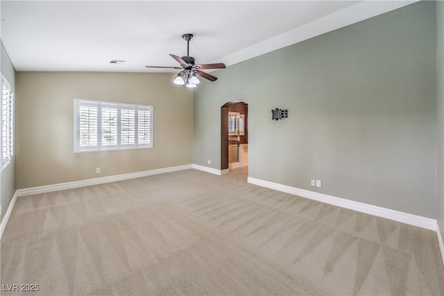 unfurnished room with arched walkways, carpet flooring, ceiling fan, lofted ceiling, and baseboards