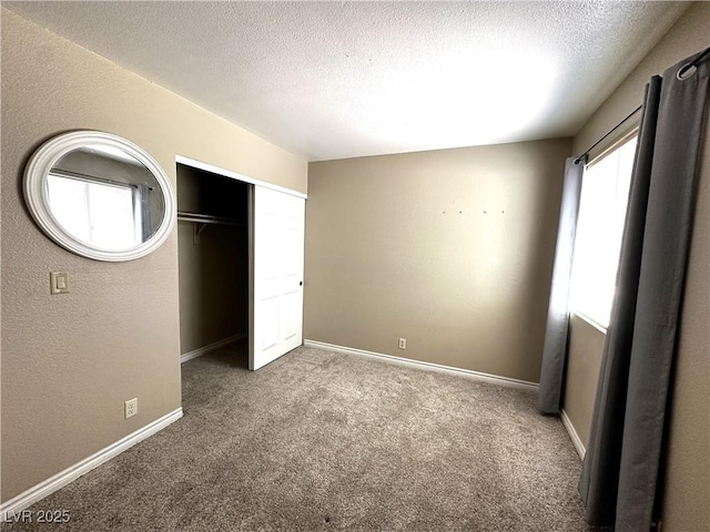 unfurnished bedroom featuring a textured ceiling, carpet, a closet, and baseboards