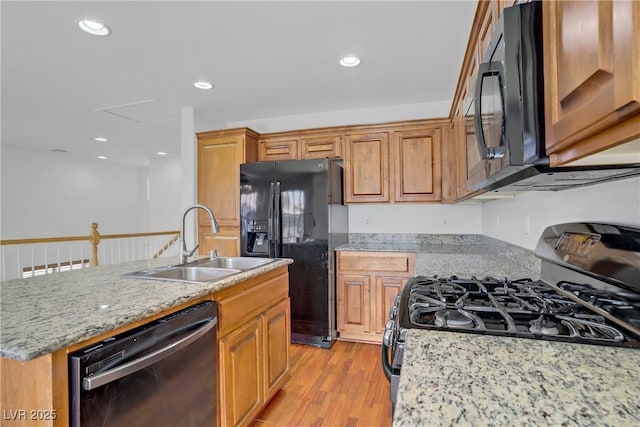 11247 Villa Trentino Ct, Las Vegas, NV 89141 - kitchen featuring black appliances, a sink, light wood-style flooring, light stone countertops, and a center island with sink
