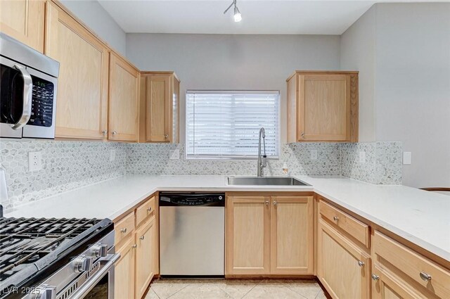kitchen with light brown cabinetry, stainless steel appliances, a sink, and decorative backsplash