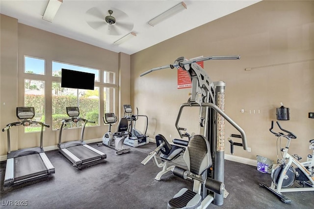 gym with a ceiling fan and baseboards