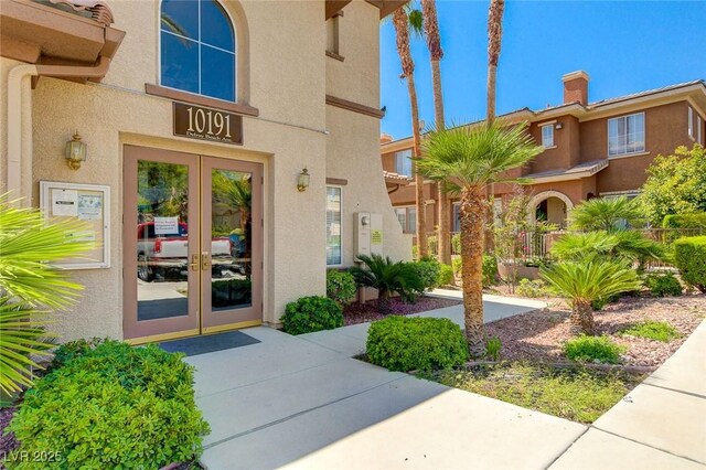 entrance to property with stucco siding, french doors, and a chimney