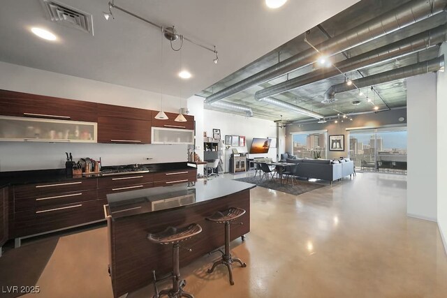900 Las Vegas Blvd Unit 715, Las Vegas, NV 89101 - kitchen with modern cabinets, finished concrete floors, dark countertops, a breakfast bar, and dark brown cabinets