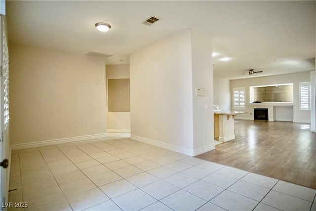 66 Sunset Bay St, Las Vegas, NV 89148 - empty room featuring a ceiling fan, a fireplace, baseboards, and light tile patterned floors