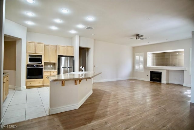 66 Sunset Bay St, Las Vegas, NV 89148 - kitchen featuring stainless steel appliances, a sink, light brown cabinets, light wood-type flooring, and a ceiling fan