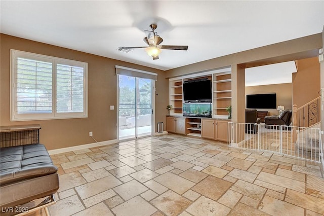 6409 Sea Swallow St, North Las Vegas, NV 89084 - unfurnished living room with baseboards, a ceiling fan, built in shelves, and stone tile floors