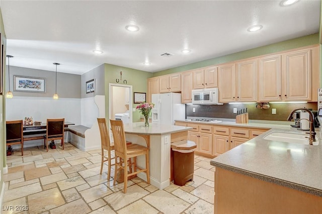 6409 Sea Swallow St, North Las Vegas, NV 89084 - kitchen featuring white appliances, a sink, stone tile flooring, a kitchen breakfast bar, and recessed lighting