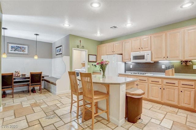 6409 Sea Swallow St, North Las Vegas, NV 89084 - kitchen featuring white appliances, light brown cabinets, light countertops, a kitchen island, and a kitchen bar