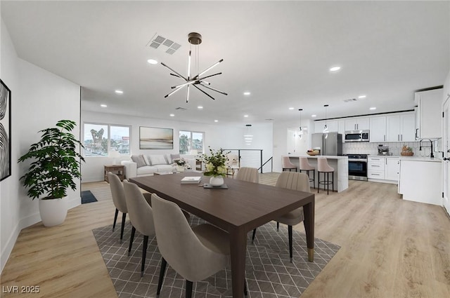 dining space featuring light wood-type flooring, recessed lighting, and a chandelier
