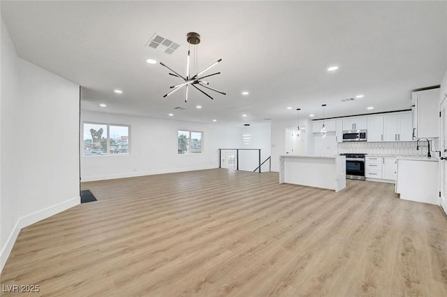 unfurnished living room featuring recessed lighting, light wood-type flooring, a chandelier, and a sink