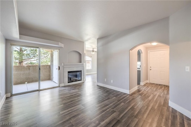 541 Indian Bluff St Unit 201, Las Vegas, NV 89145 - unfurnished living room featuring ceiling fan, arched walkways, wood finished floors, baseboards, and a tiled fireplace