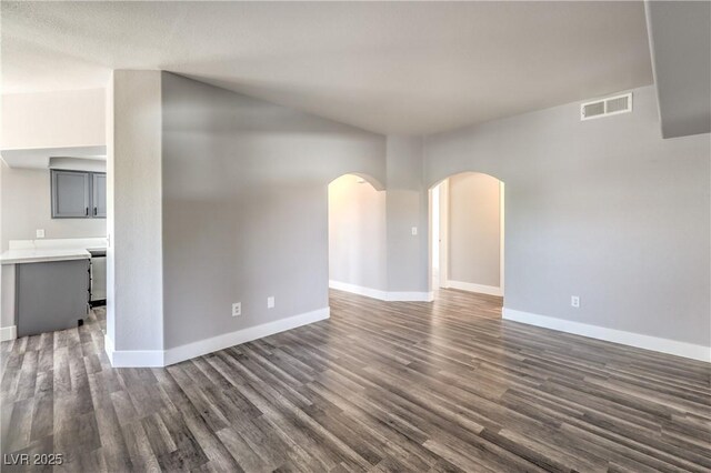 541 Indian Bluff St Unit 201, Las Vegas, NV 89145 - unfurnished living room featuring arched walkways, baseboards, and dark wood-type flooring