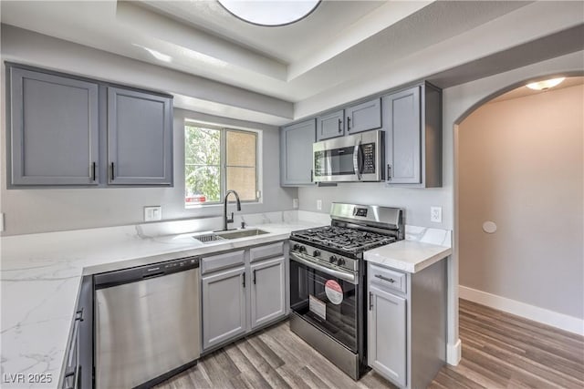 541 Indian Bluff St Unit 201, Las Vegas, NV 89145 - kitchen featuring stainless steel appliances, a sink, arched walkways, light wood-style flooring, and light stone countertops