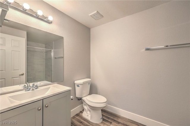 541 Indian Bluff St Unit 201, Las Vegas, NV 89145 - bathroom featuring wood finished floors, toilet, a tile shower, vanity, and baseboards