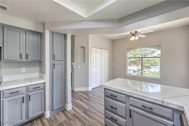 541 Indian Bluff St Unit 201, Las Vegas, NV 89145 - kitchen featuring gray cabinetry, light wood-style floors, baseboards, ceiling fan, and light stone counters
