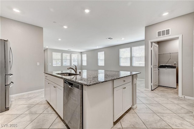 kitchen with a sink, appliances with stainless steel finishes, white cabinetry, an island with sink, and light tile patterned floors