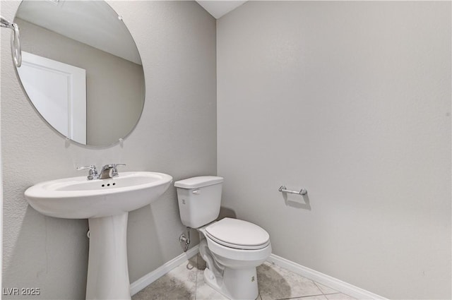 bathroom featuring toilet, tile patterned floors, and baseboards