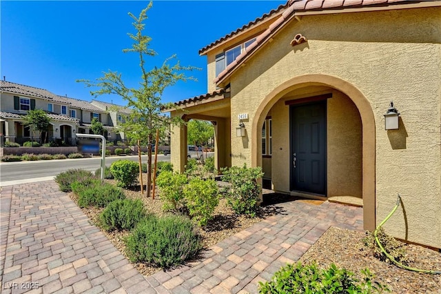 doorway to property featuring stucco siding, a tiled roof, and a residential view