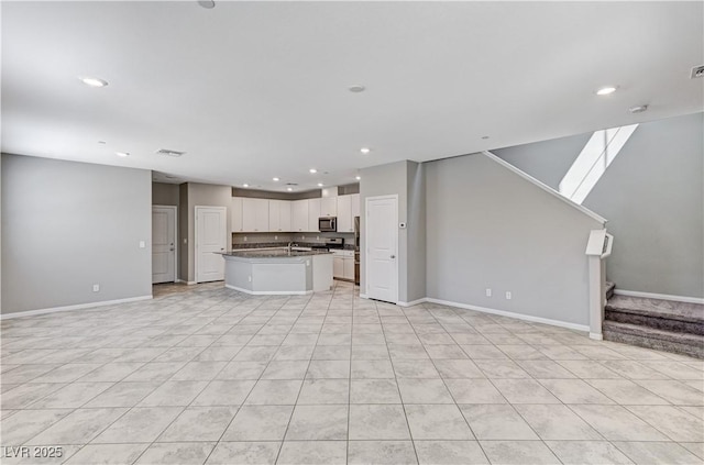 unfurnished living room featuring baseboards, stairway, recessed lighting, light tile patterned flooring, and a sink