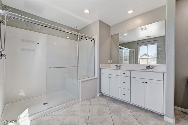 full bath featuring a stall shower, double vanity, baseboards, and tile patterned floors