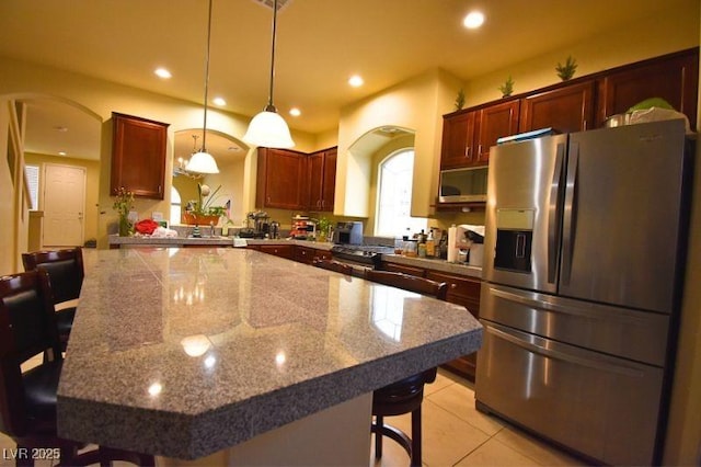 6339 Sharp Rock Ct, Las Vegas, NV 89139 - kitchen with appliances with stainless steel finishes, a kitchen bar, decorative light fixtures, arched walkways, and light stone countertops
